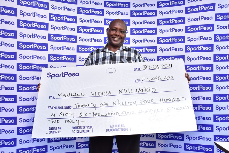 Arsenal fan Maurice Vidija Muliango poses with his winners check after correctly predicting 13 games to win the SportPesa Midweek Jackpot.