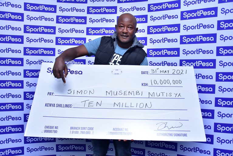 Simon Musembi Mutisya poses with his winners checque of KSHs 10,000,000 after he became the fourth winner of the SportPesa Midweek Jackpot this year.